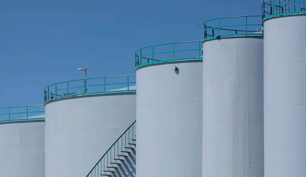 White above-ground petroleum storage tanks with a stairway and roof railings
